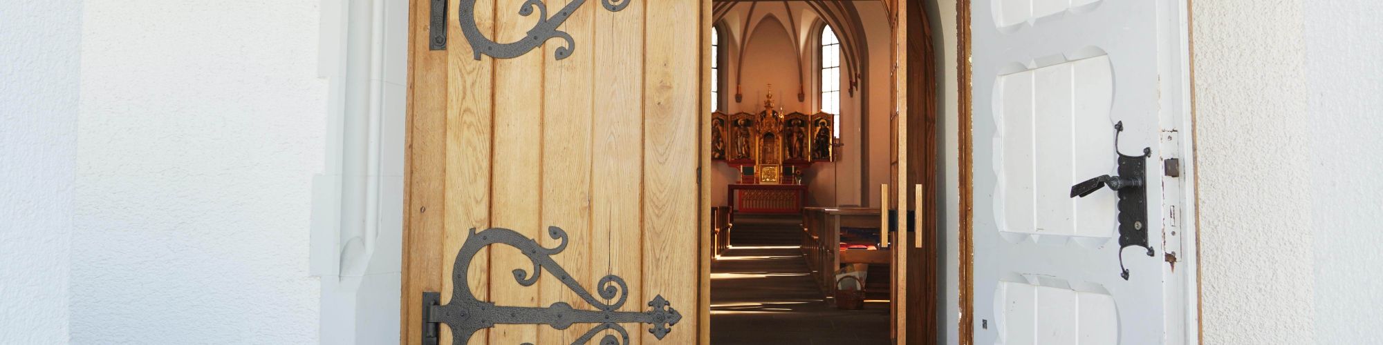 Offene Kirchentür mit Blick hinein